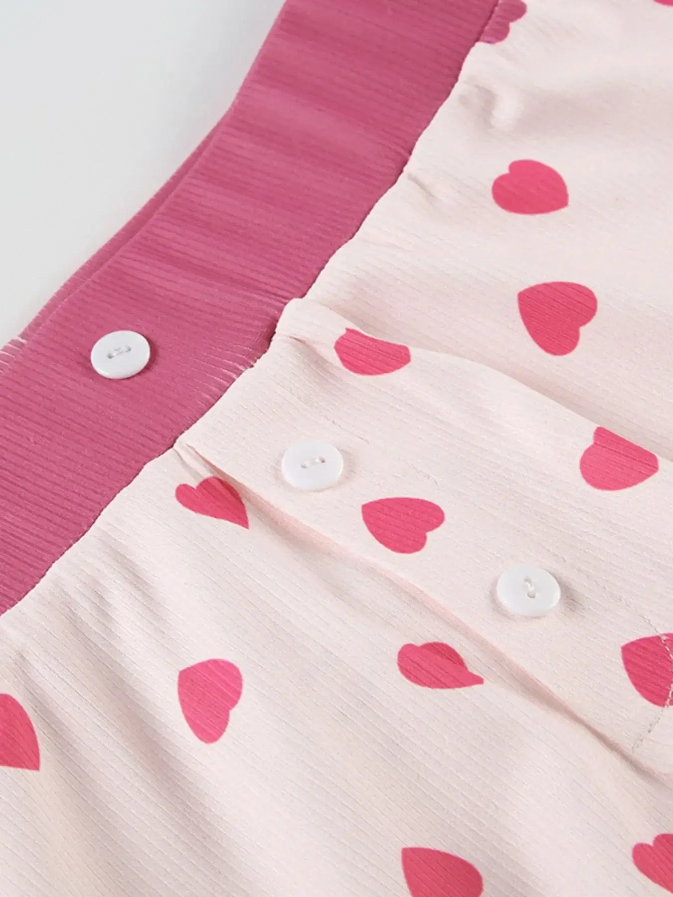 Close-up of Heart Print Top and Shorts Loungewear Set featuring pink heart patterns and buttons.
