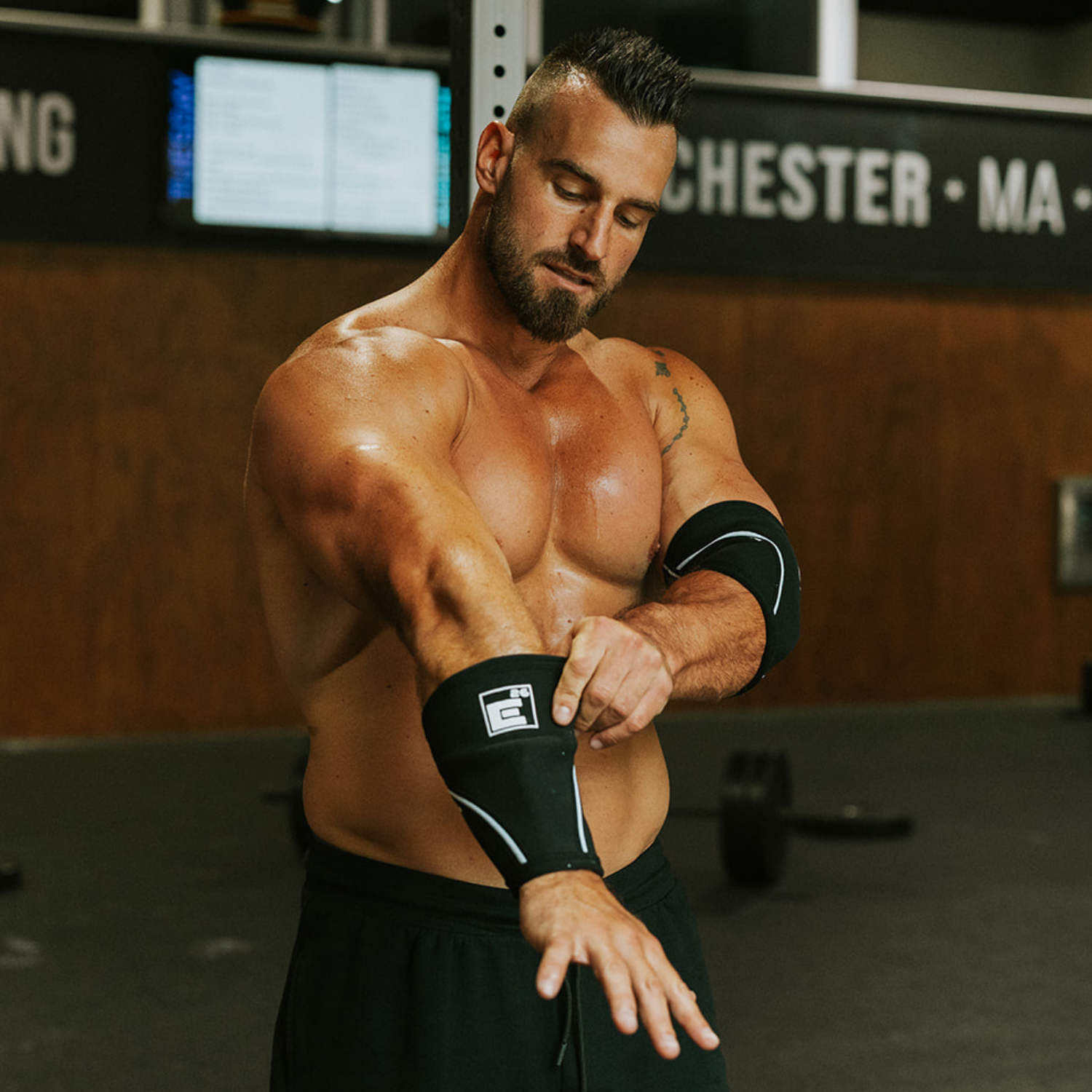 Athlete wearing 5mm Elbow Sleeves while preparing for a workout in the gym.