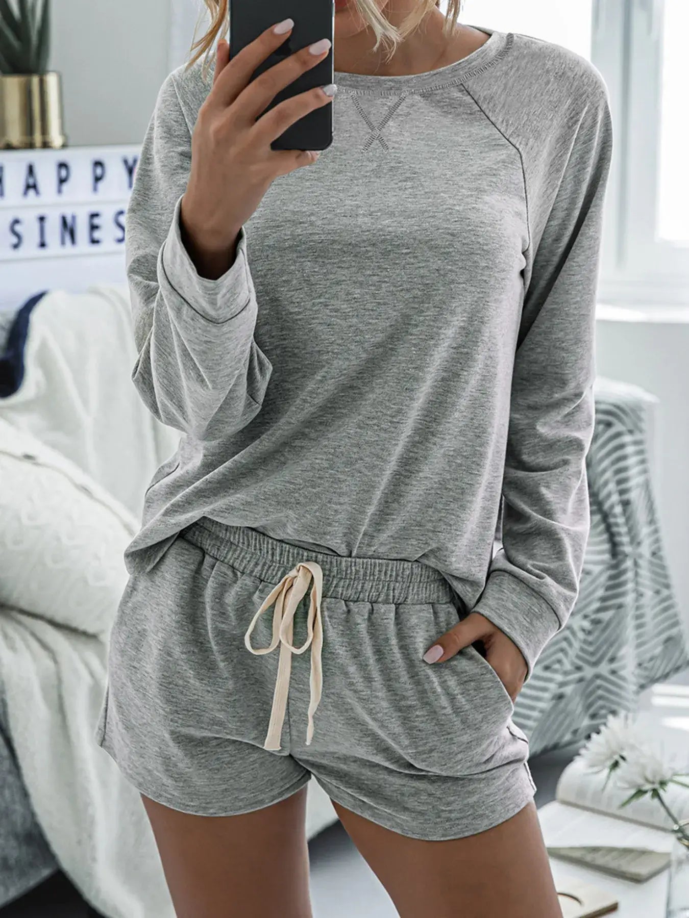 Model wearing Round Neck Raglan Sleeve Top and Shorts Lounge Set in gray with pockets and drawstring.