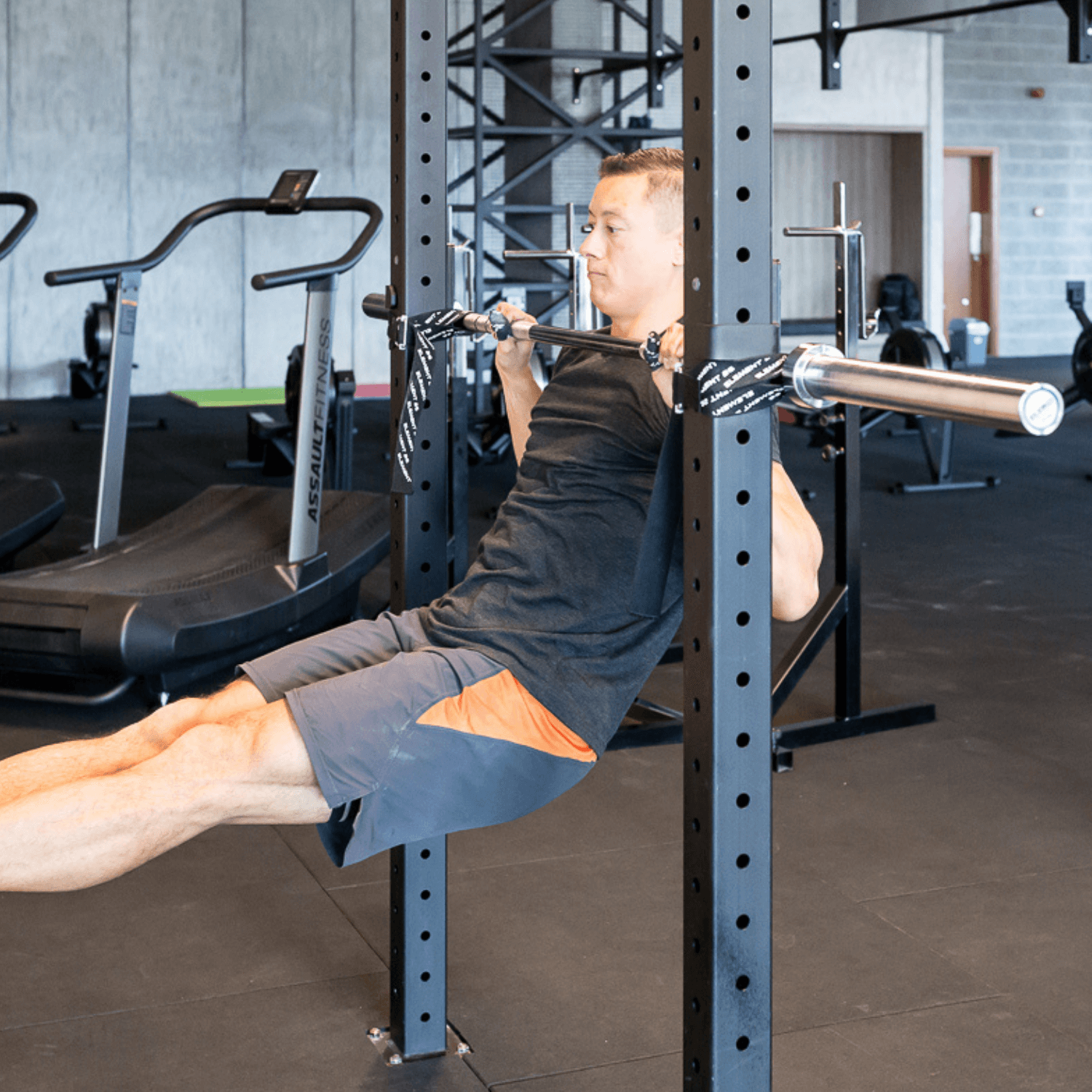 Man performing muscle-up training using Barbelts in a gym setting.