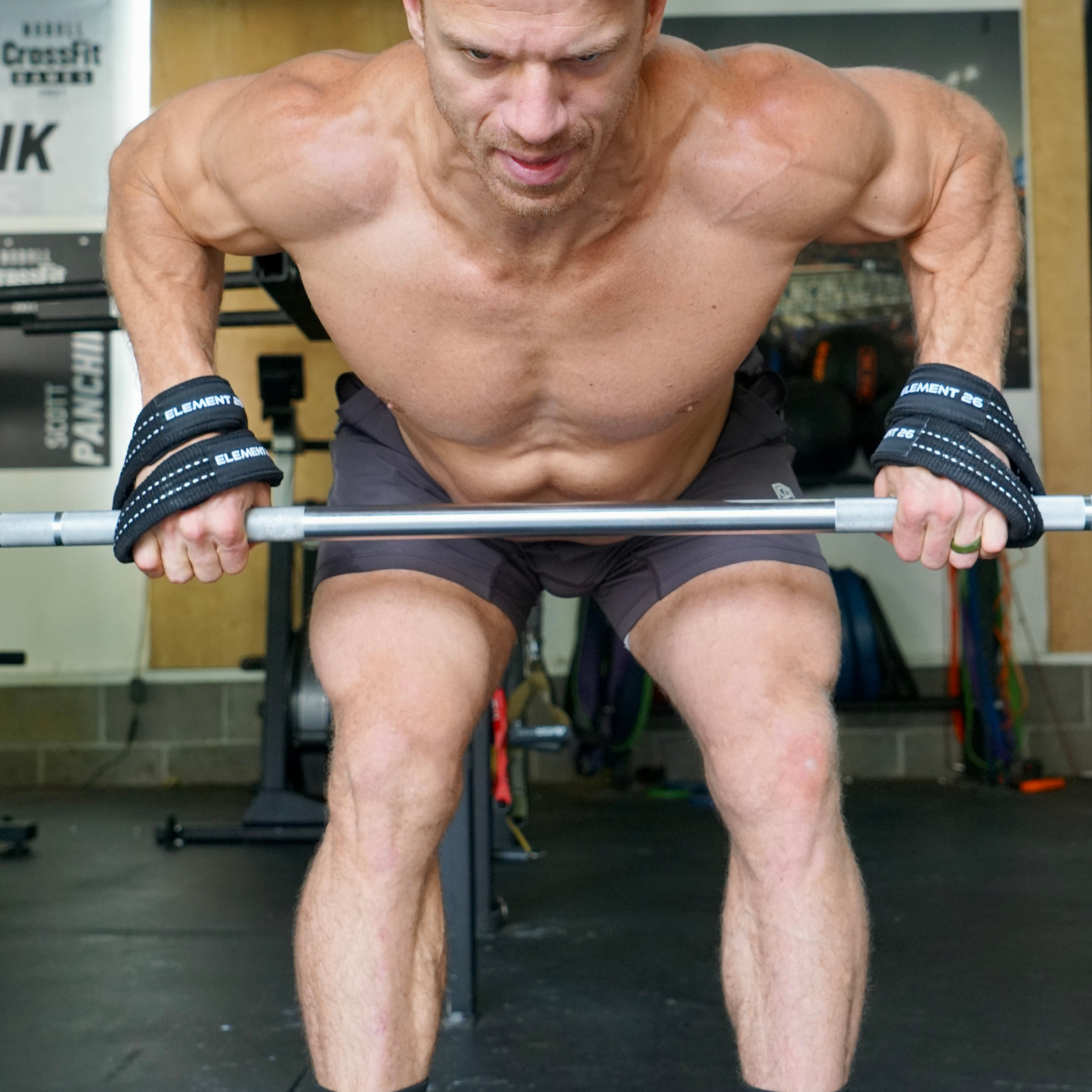 Muscular man using Padded Figure 8 Weightlifting Straps during a rowing exercise in a gym setting.