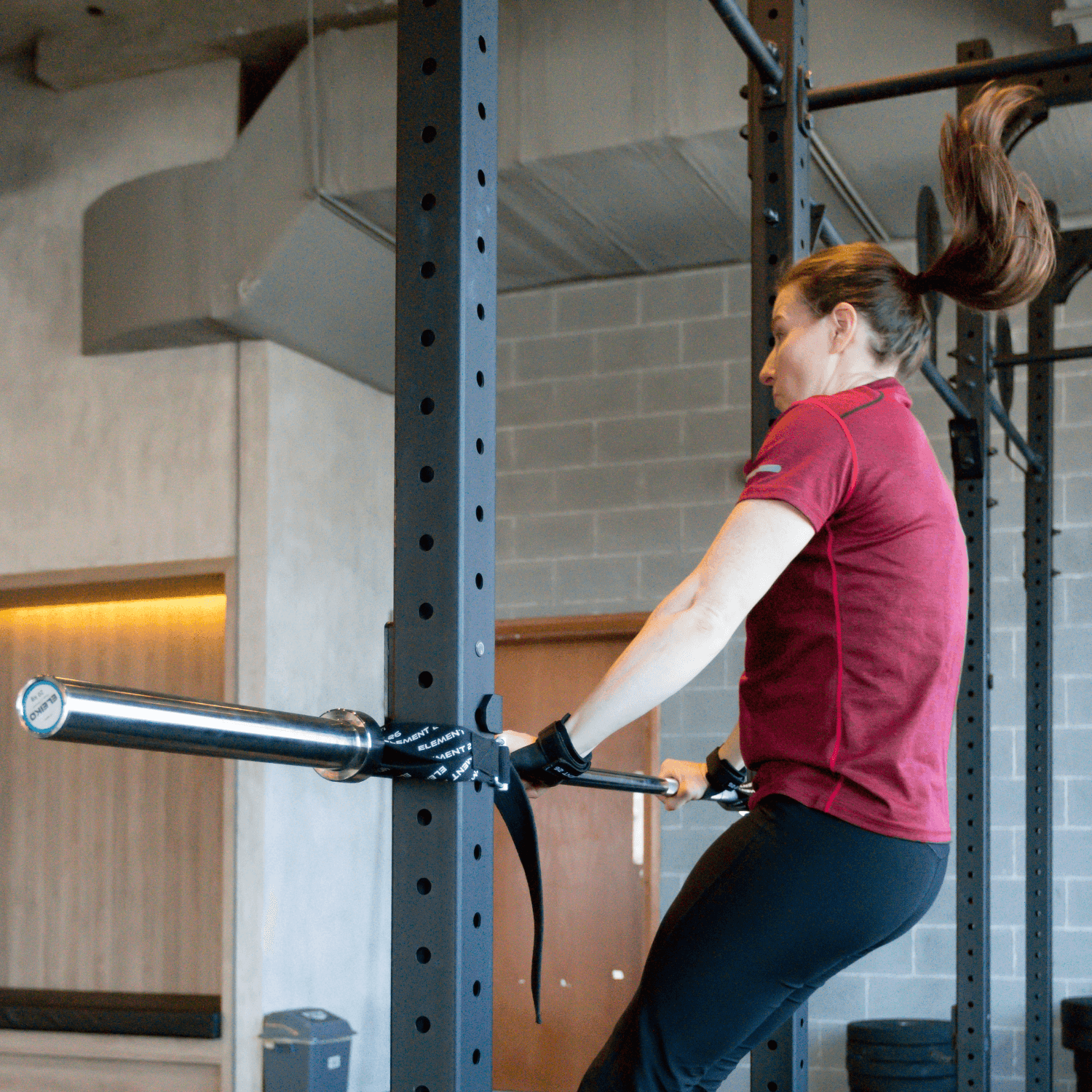 Woman using Barbelts for muscle-up training in a gym, showcasing versatility and premium build quality.