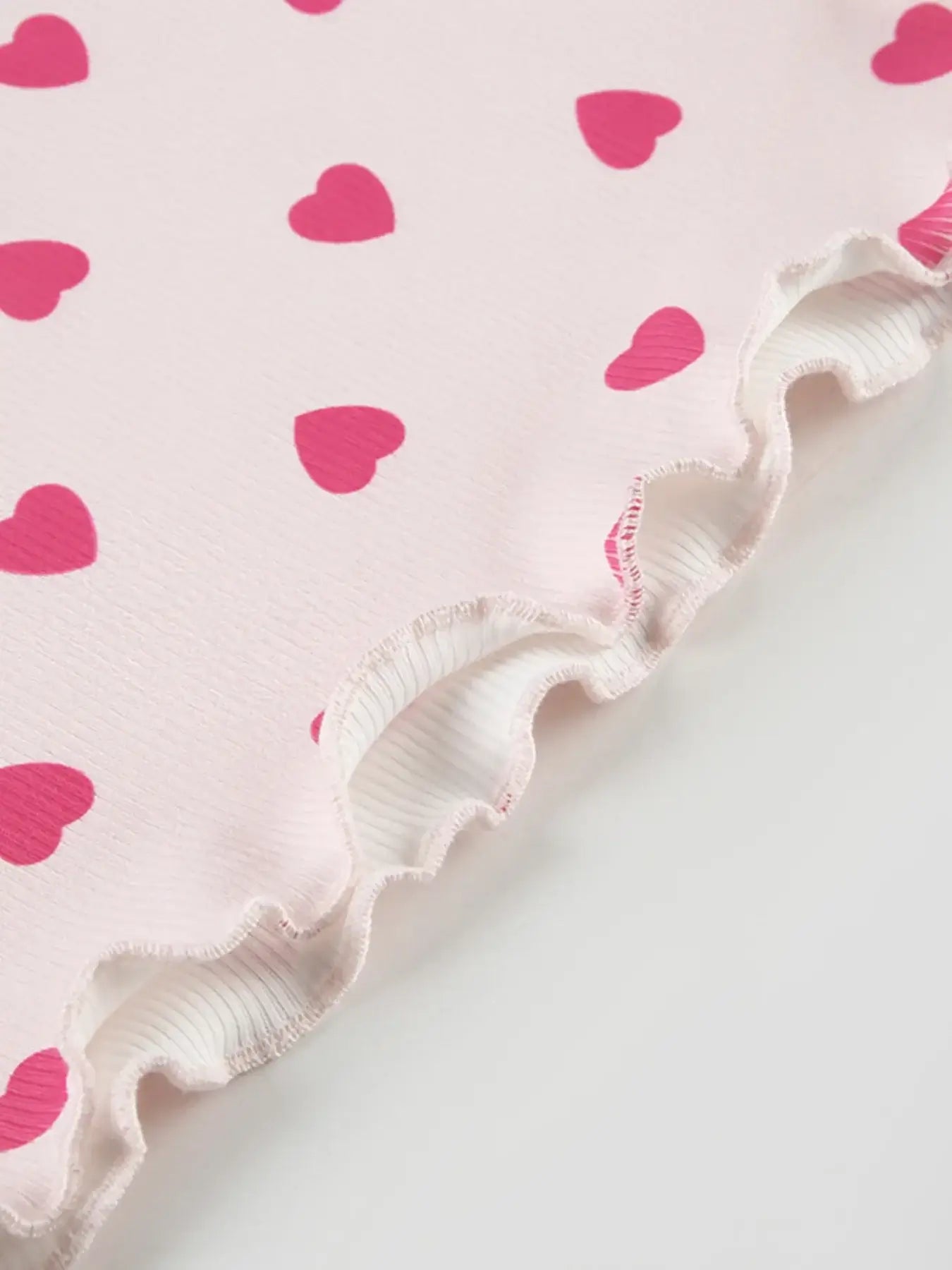 Close-up of the Heart Print Top and Shorts Loungewear Set showcasing pink heart patterns and ruffled edges.