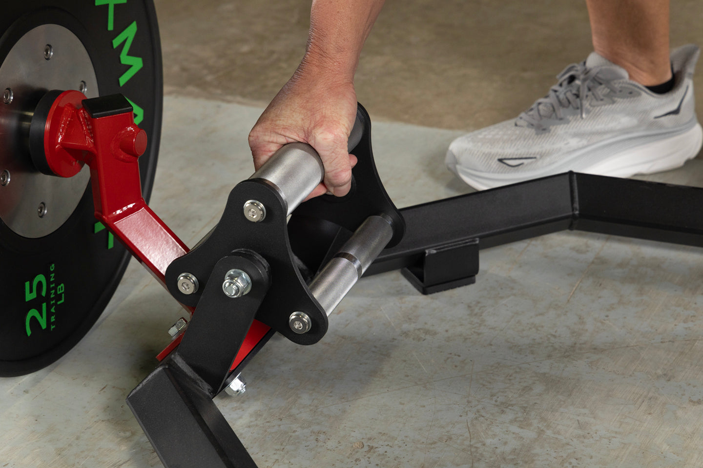 A close-up of a hand gripping the revolving handle of an Olympic Hex Trap Shrug Barbell with weight plates.