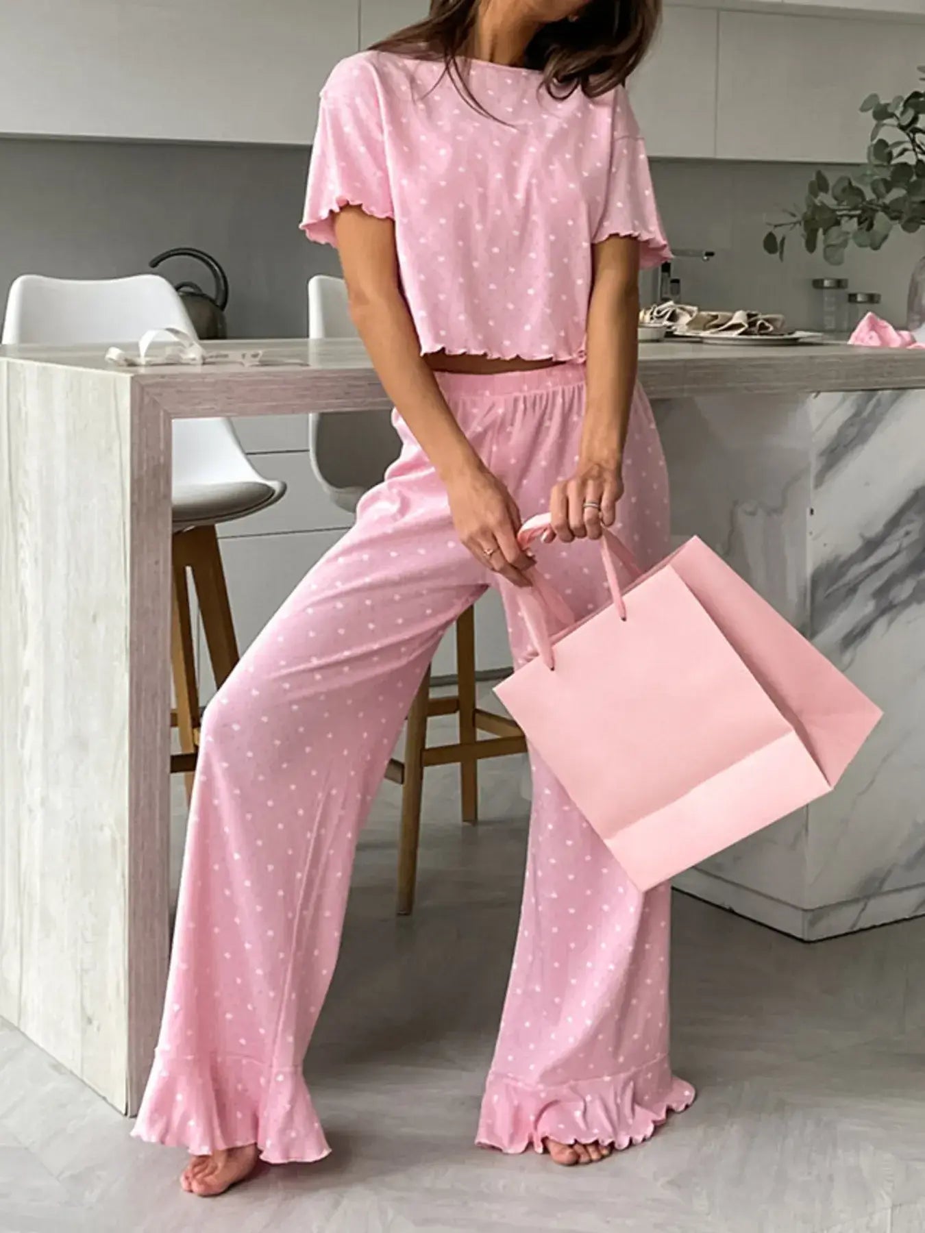 Polka Dot Round Neck Top and Pants Lounge Set worn by a woman holding a pink bag in a modern kitchen.