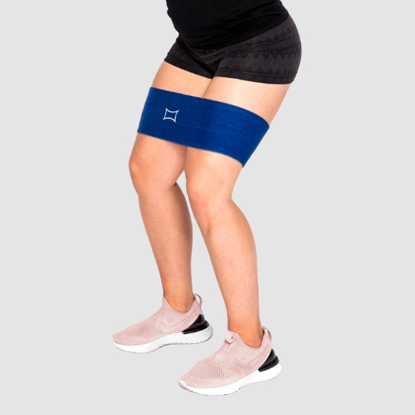 Person using Big Ass Hip Circle for glute activation, wearing athletic shorts and sneakers.
