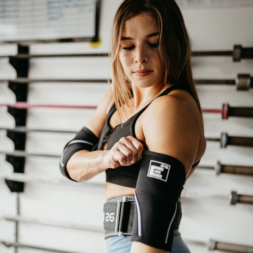 Element 26 5mm Elbow Sleeves worn by a athlete adjusting them during a workout in the gym.