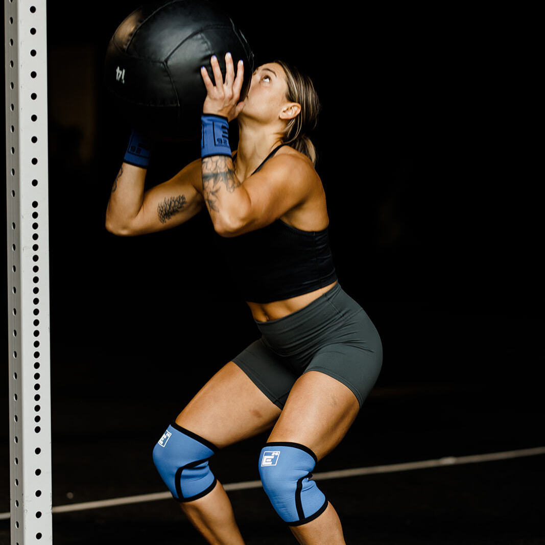 Athlete using 6mm Knee Sleeves while lifting a medicine ball during a workout.