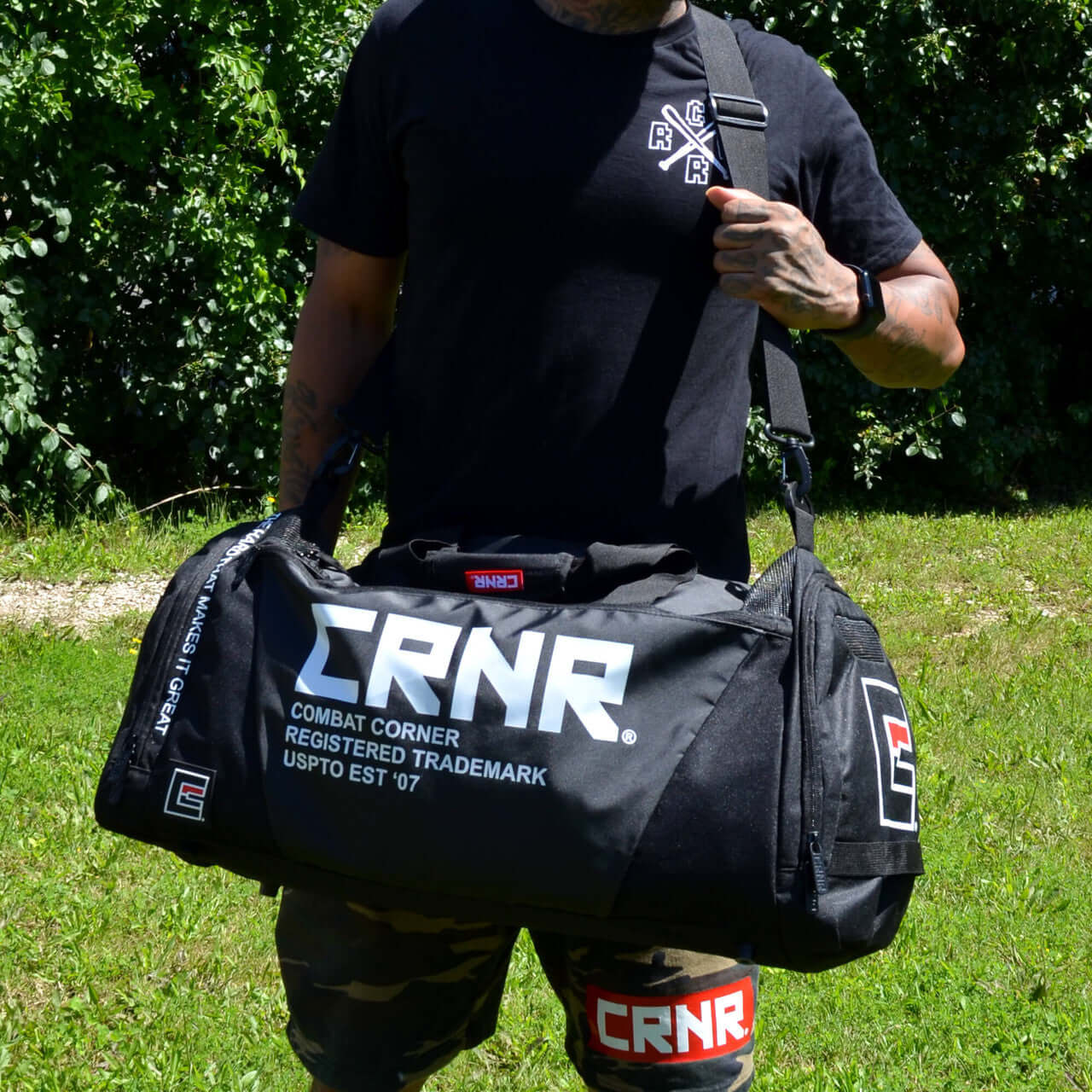 Essential Gear Duffel Bag by COMBAT CORNER being carried outdoors by a man in a sporty outfit.