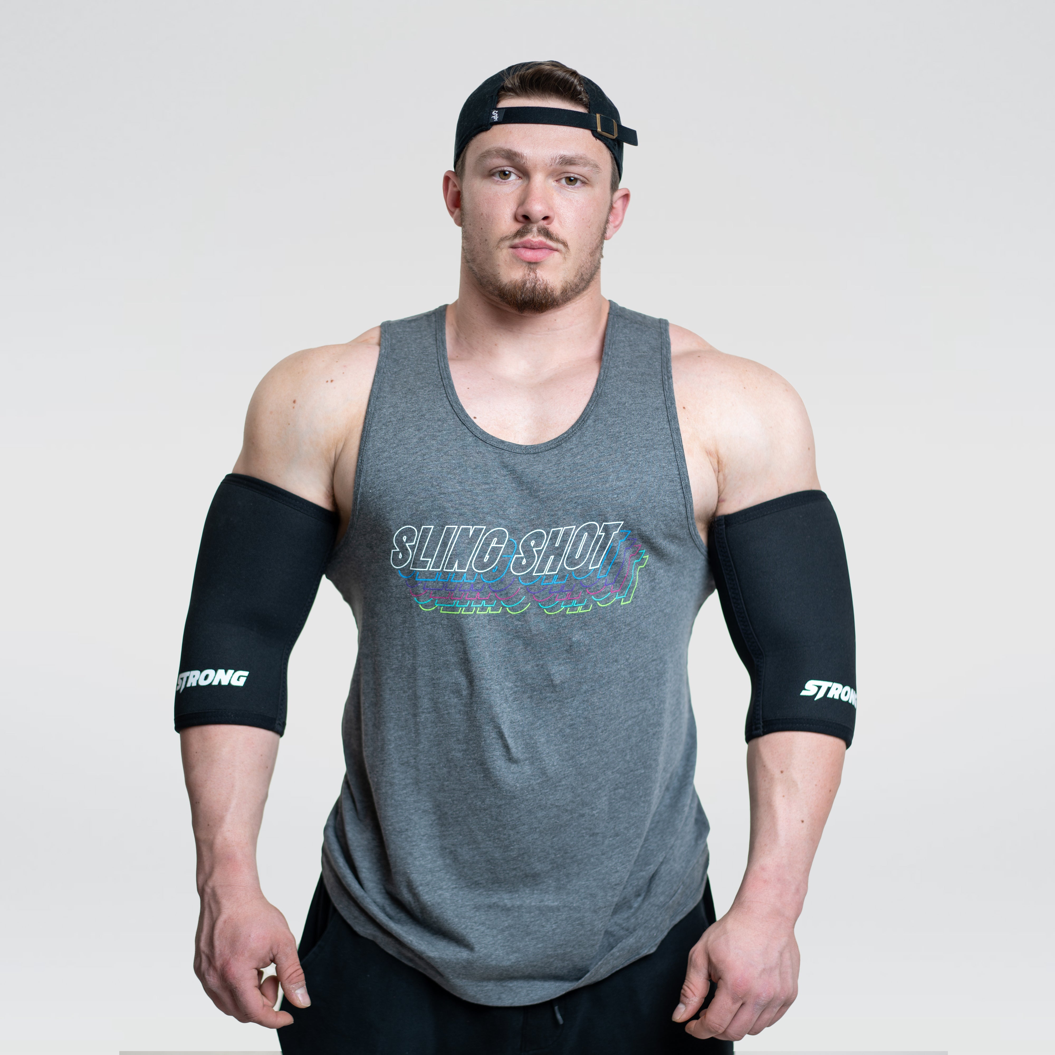 Man wearing Strong Elbow Sleeves for support and compression during weight training.