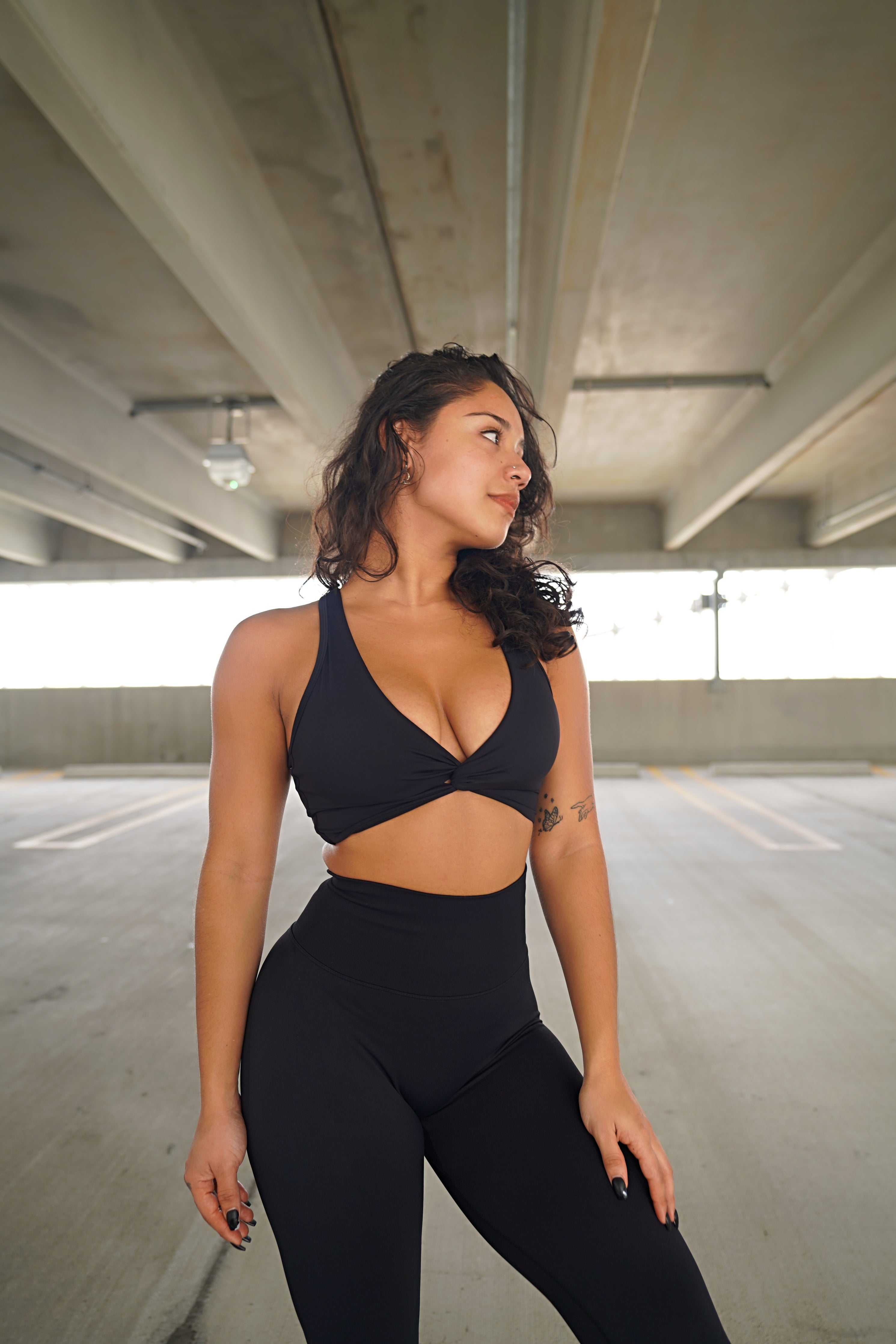 Model showcasing the Impact Sports Bra - Black in a stylish athletic setting, emphasizing fit and support.