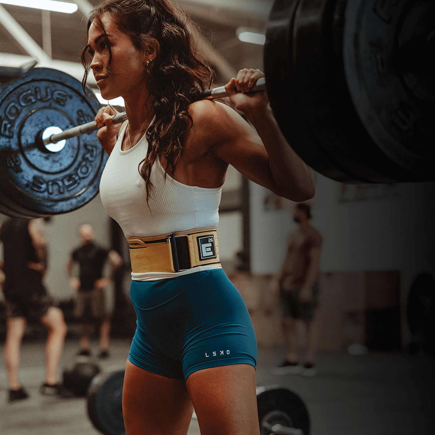 Woman lifting weights in a gym wearing a Self Locking Weightlifting Belt for maximum support and stability.