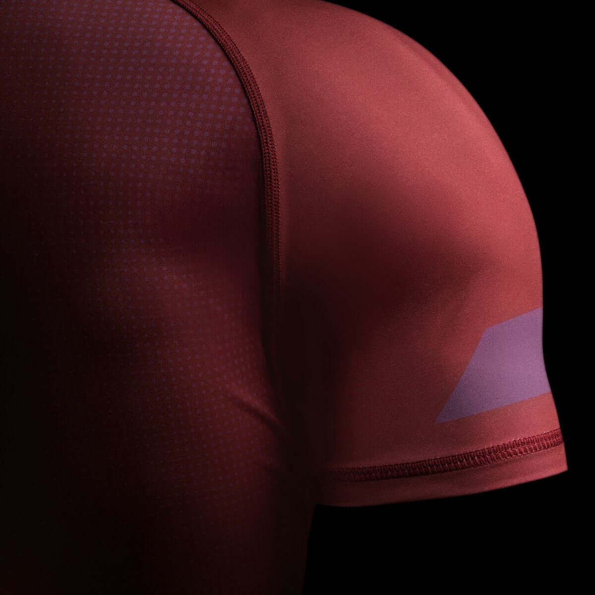 Hayabusa Core Short Sleeve Rash Guard featuring a close-up view of the shoulder and sleeve design on a maroon background.