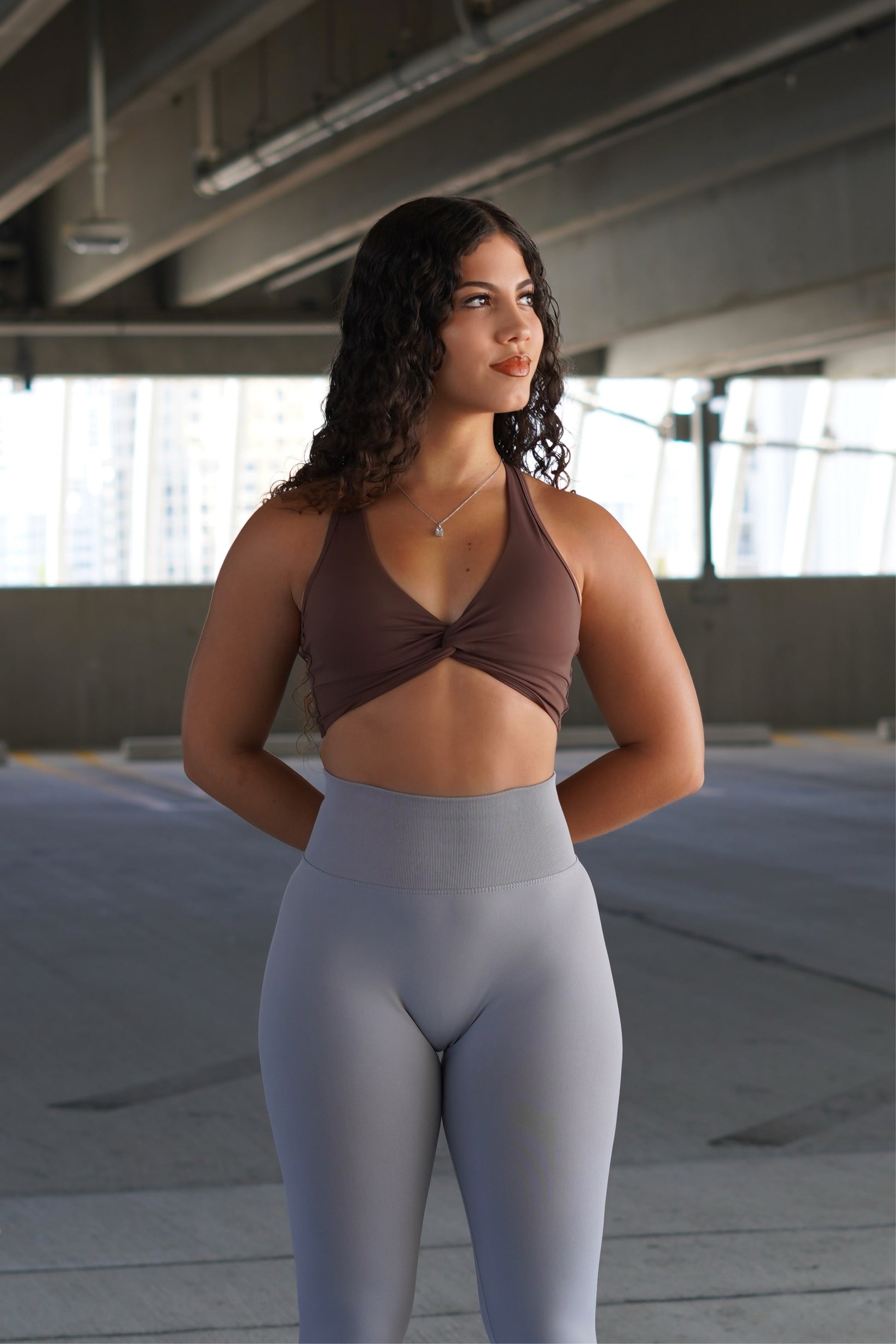 Impact Sports Bra - Brown model wearing a supportive sports bra paired with high-rise leggings in a modern urban setting.