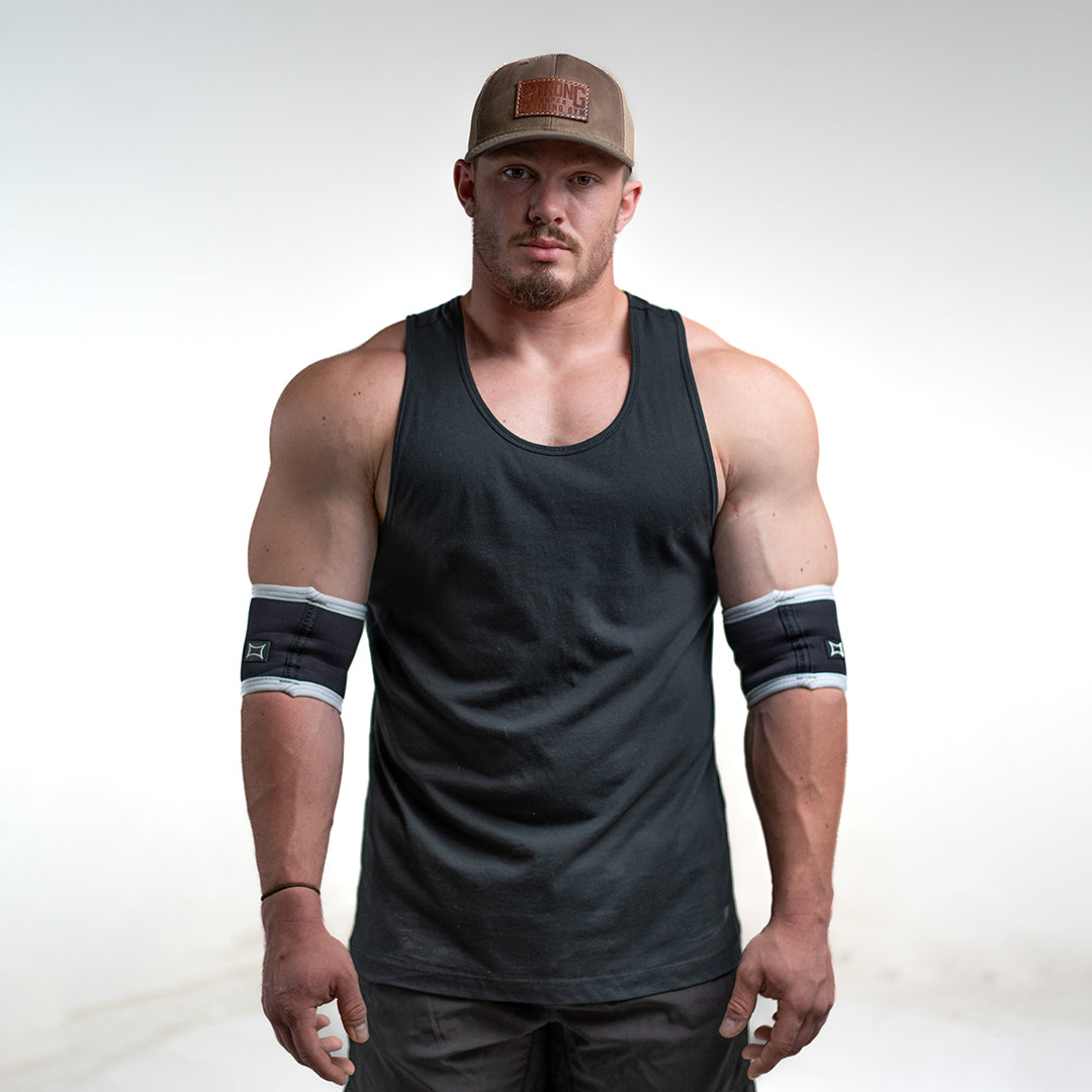 Man showcasing Raw Elbow Sleeves in a black tank top, emphasizing strength and style.