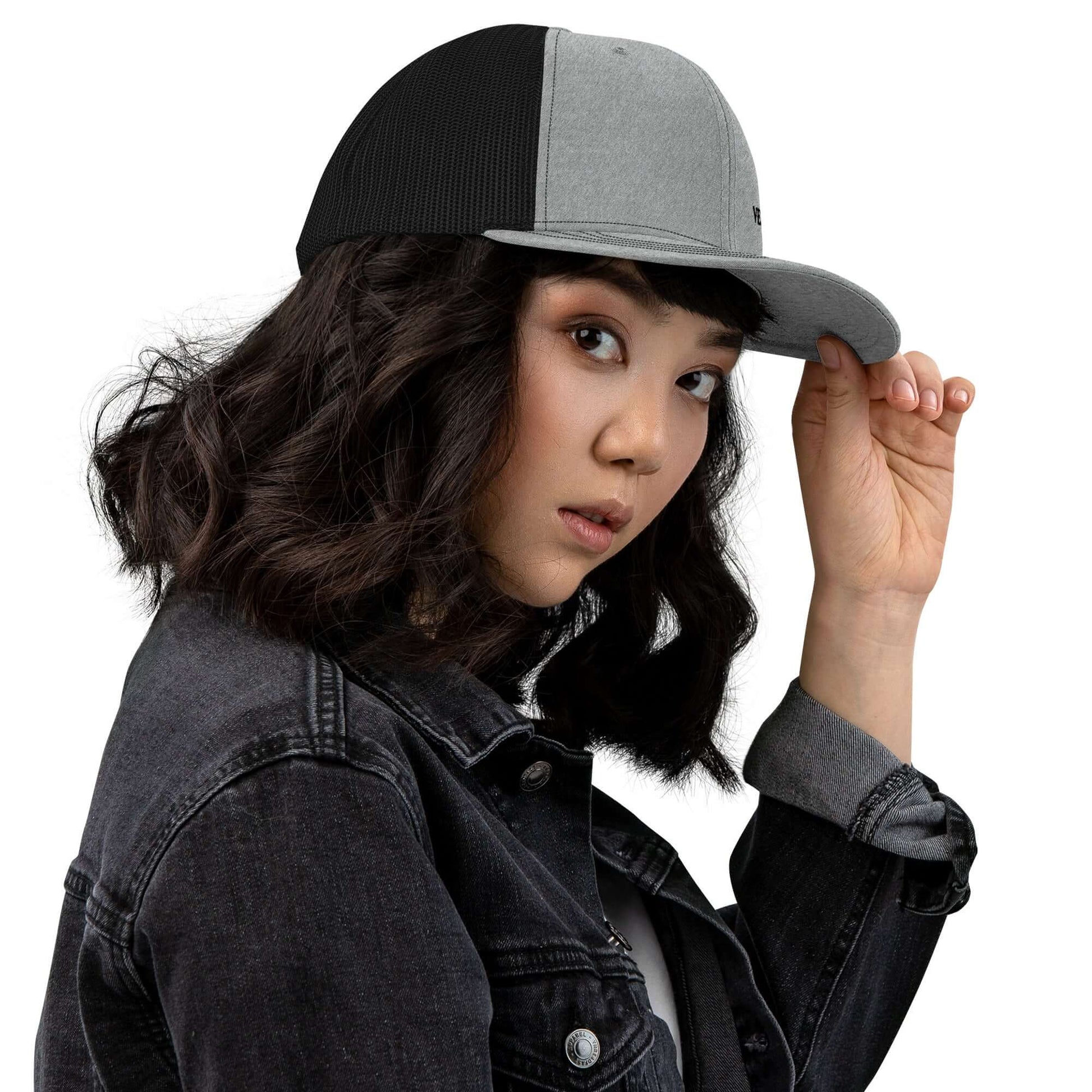 Stylish woman wearing a Trucker Hat By Vellmara with black and gray panels, showcasing adjustable fit and curved visor.