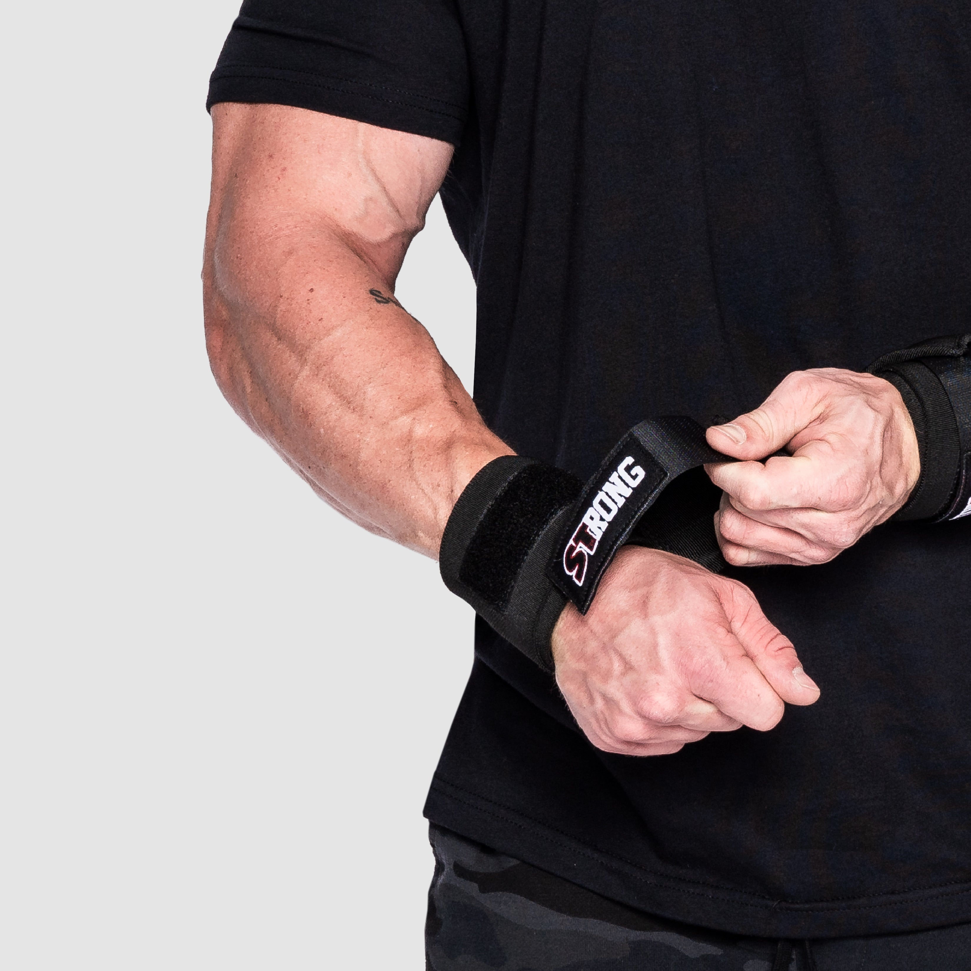 Close-up of a lifter securing Strong Wrist Wraps for maximum wrist support.
