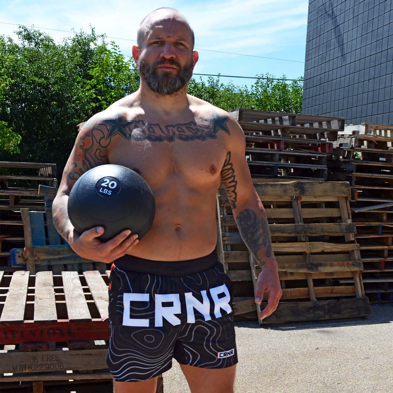 FORM TRAINING SHORTS by Combat Corner model holding a 20 lbs medicine ball outdoors.