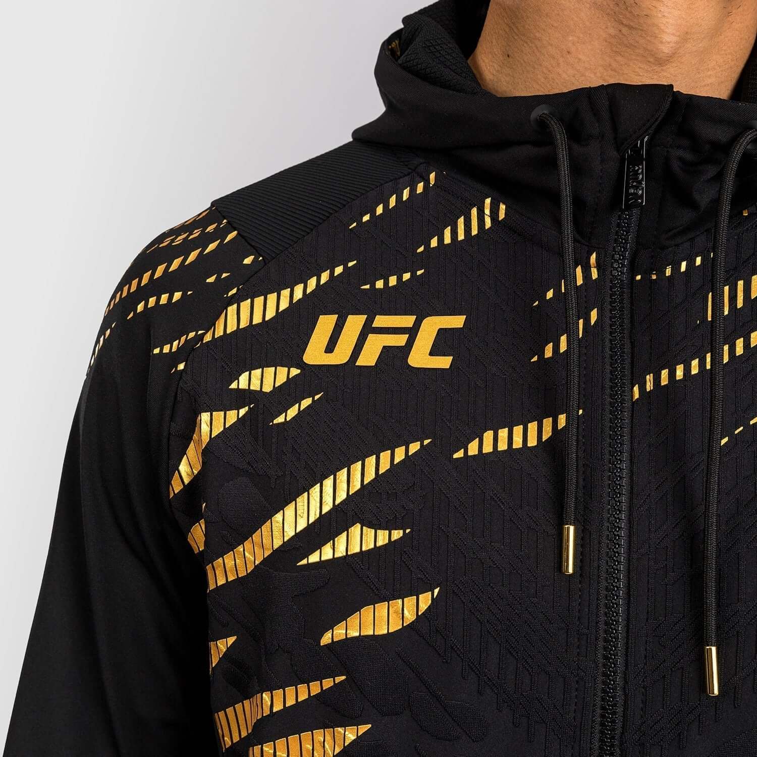 UFC Fusion Authentic Fight Night Walkout Hoodie close-up with black and gold design, featuring prominent UFC logo.