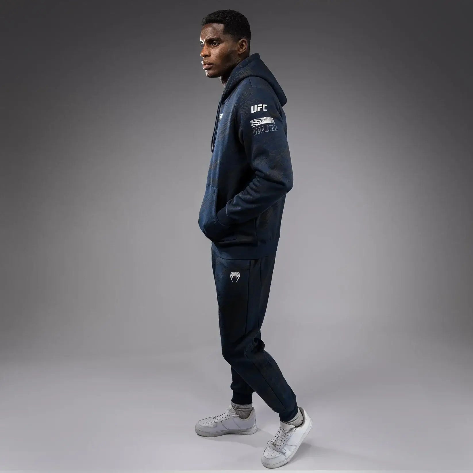 UFC Fusion Fight Week Pullover Hoodie worn by model showing side view in dark color scheme with UFC branding.