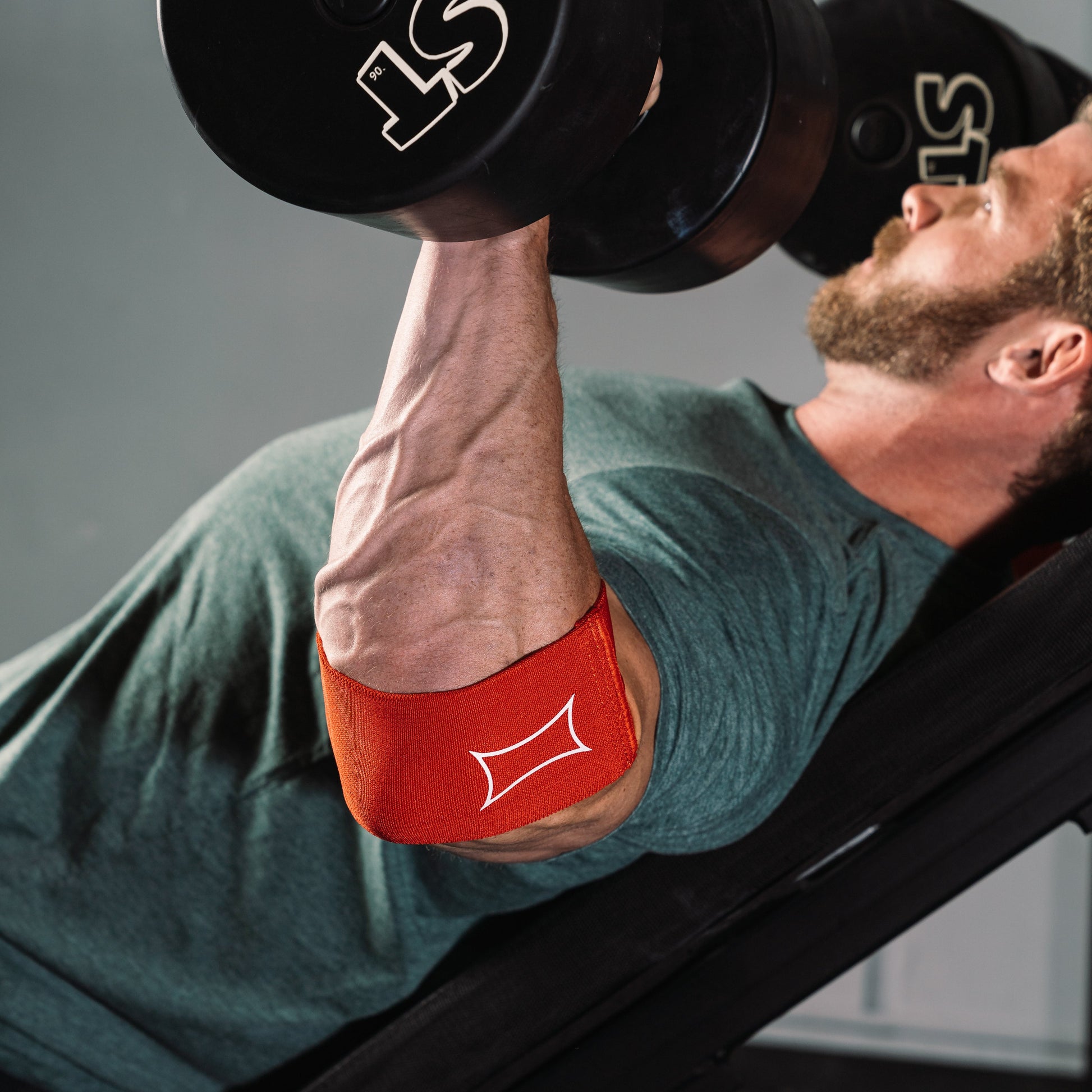 Man using Compression Cuff 2.0 while lifting dumbbells for enhanced joint support in training.