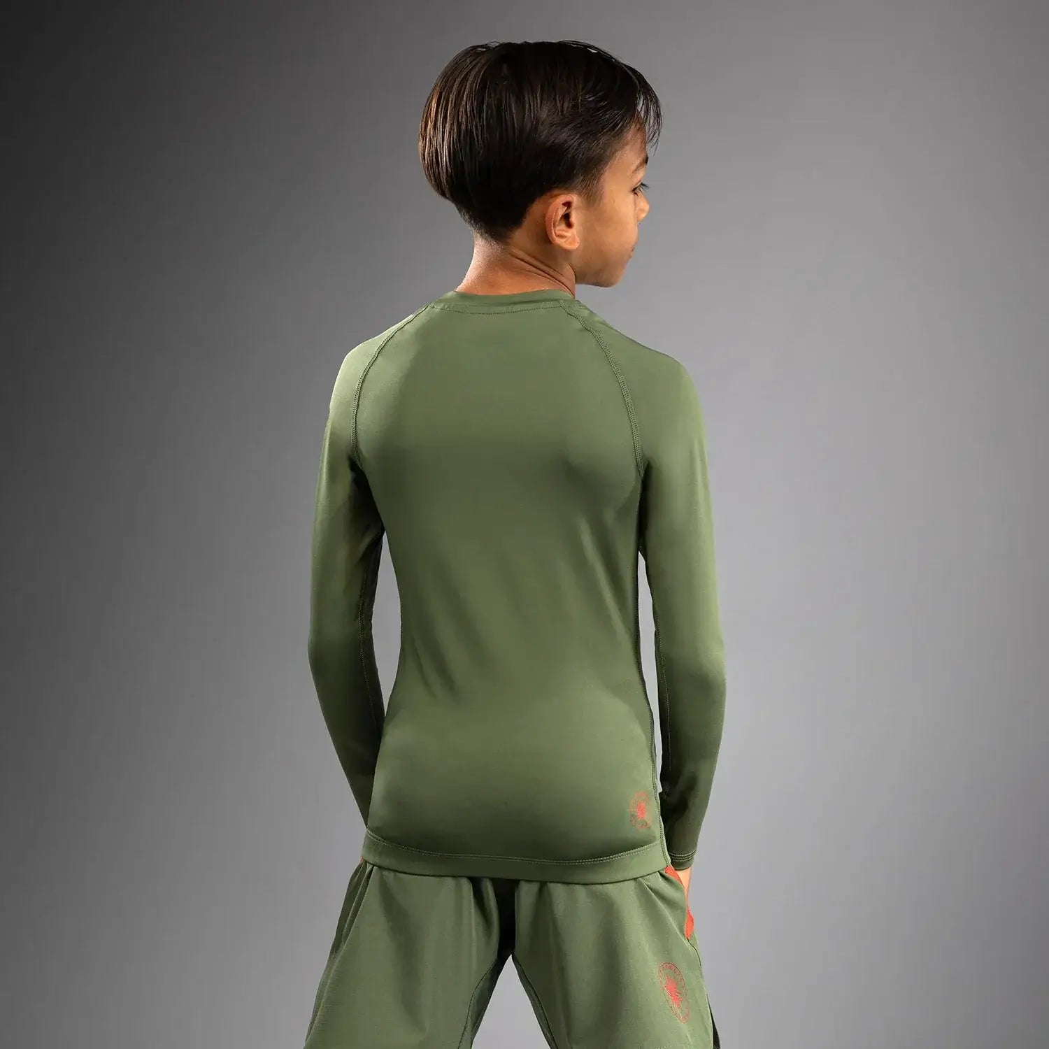 Venum Contender Kids Rash Guard - Long Sleeve worn by a boy, showcasing the back view of the athletic design.