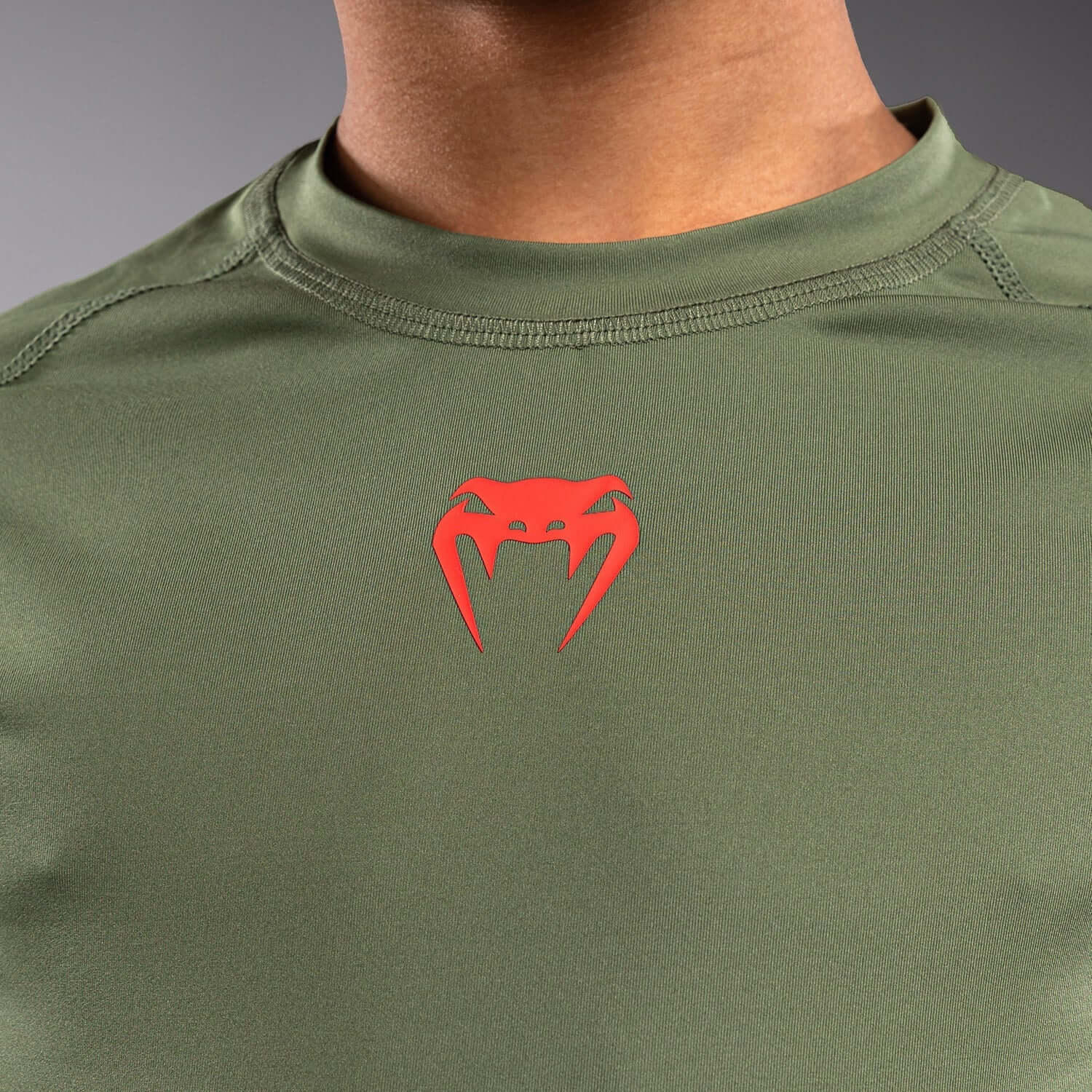 Venum Contender Kids Rash Guard - Long Sleeve showcasing red logo on olive green fabric.